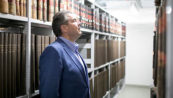 Besuch des Bundesministers des Auswärtigen Sigmar Gabriel im Politischen Archiv. Er steht zwischen zwei Magazinregalen und sich Archivalien an.